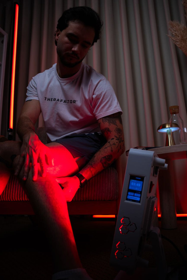 Homem a fazer terapia de luz vermelha no joelho com o painel TheraPRO, para recuperação muscular